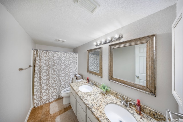 bathroom with a textured ceiling, vanity, toilet, and tile patterned floors