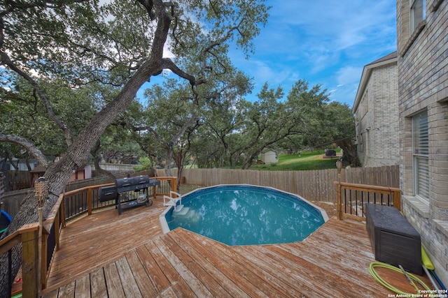 view of pool with grilling area and a wooden deck