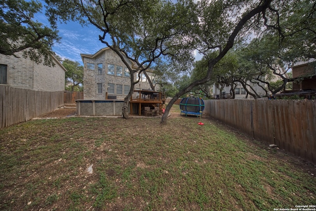 view of yard featuring a trampoline and a deck