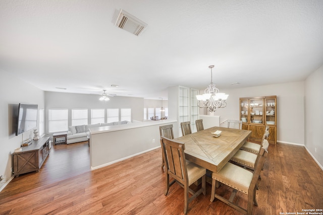 dining room with ceiling fan with notable chandelier, hardwood / wood-style flooring, and a wealth of natural light