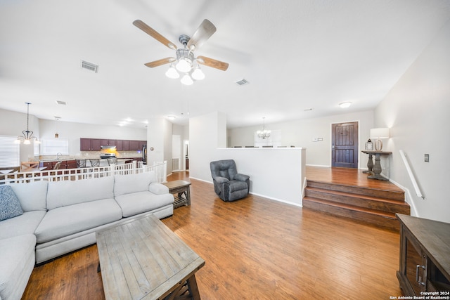 living room with ceiling fan with notable chandelier and hardwood / wood-style flooring