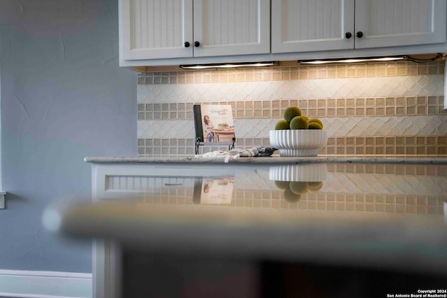 interior details with decorative backsplash and white cabinetry