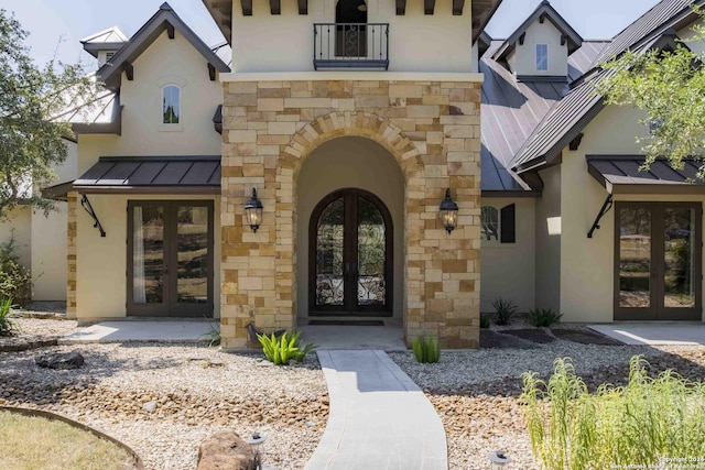 doorway to property featuring stone siding, french doors, metal roof, and a standing seam roof