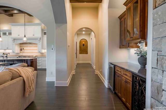 corridor with dark wood-type flooring, wine cooler, and beam ceiling