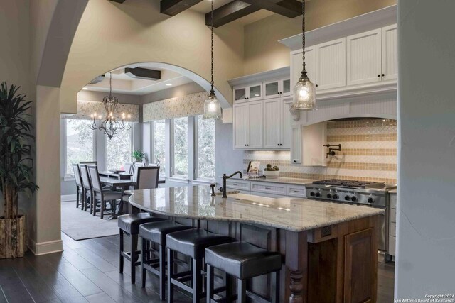 kitchen with a center island with sink, built in appliances, and white cabinetry