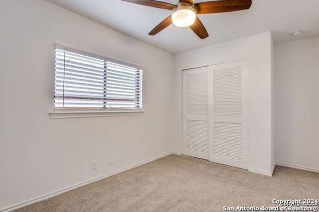 unfurnished bedroom with light carpet, ceiling fan, and a closet