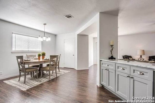 dining space with dark hardwood / wood-style flooring, an inviting chandelier, and a textured ceiling