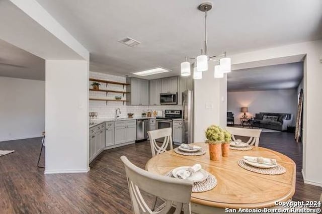 dining room with dark wood-type flooring, a chandelier, and sink