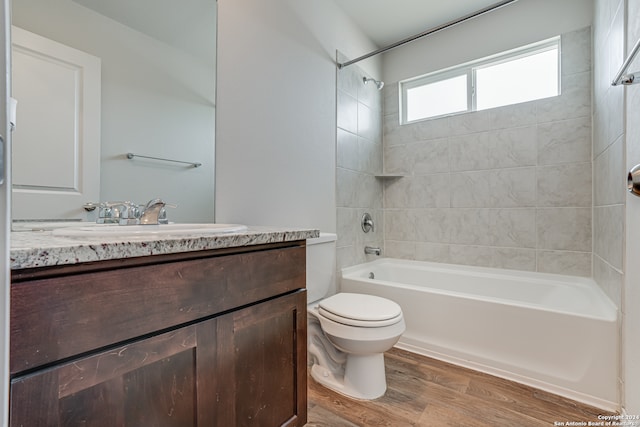 full bathroom with tiled shower / bath combo, vanity, toilet, and hardwood / wood-style floors