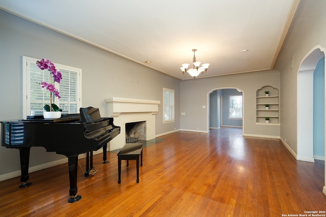 misc room featuring built in features, ornamental molding, a notable chandelier, and wood-type flooring