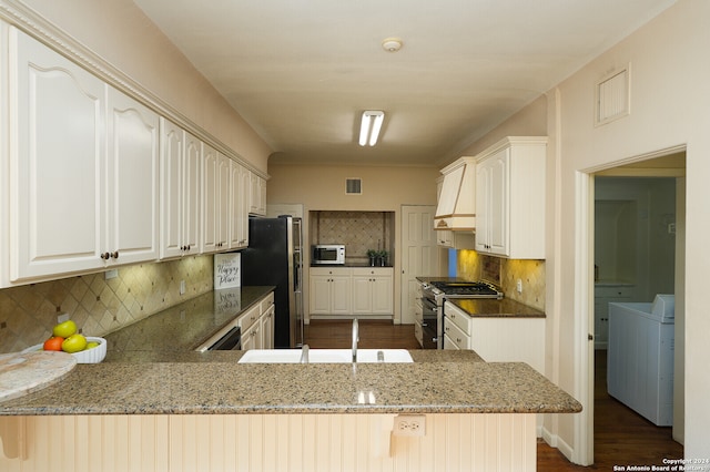 kitchen with light stone countertops, gas stove, washer / clothes dryer, kitchen peninsula, and sink