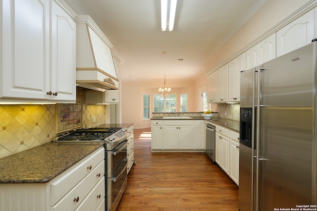 kitchen with hardwood / wood-style floors, appliances with stainless steel finishes, a notable chandelier, white cabinetry, and kitchen peninsula