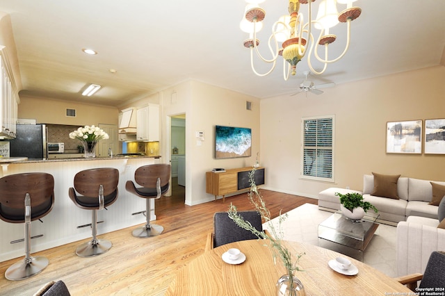 dining room featuring light hardwood / wood-style flooring and ceiling fan with notable chandelier