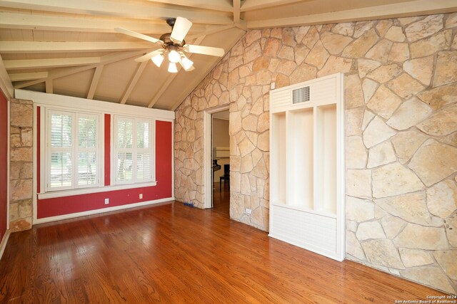 empty room with vaulted ceiling with beams, ceiling fan, visible vents, and wood finished floors