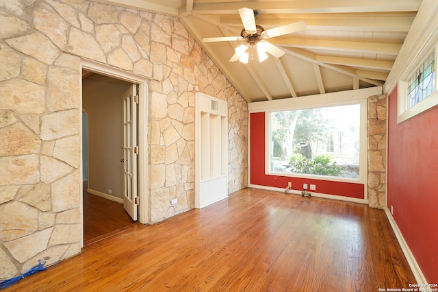 empty room featuring beamed ceiling, wood-type flooring, high vaulted ceiling, and ceiling fan