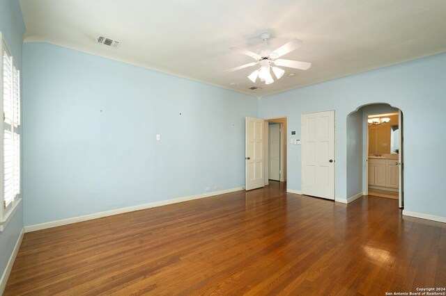 unfurnished room featuring arched walkways, ceiling fan, wood finished floors, visible vents, and baseboards