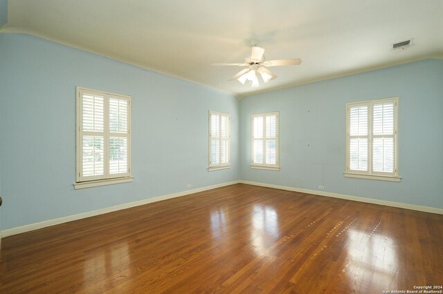 empty room featuring a ceiling fan, visible vents, baseboards, and wood finished floors