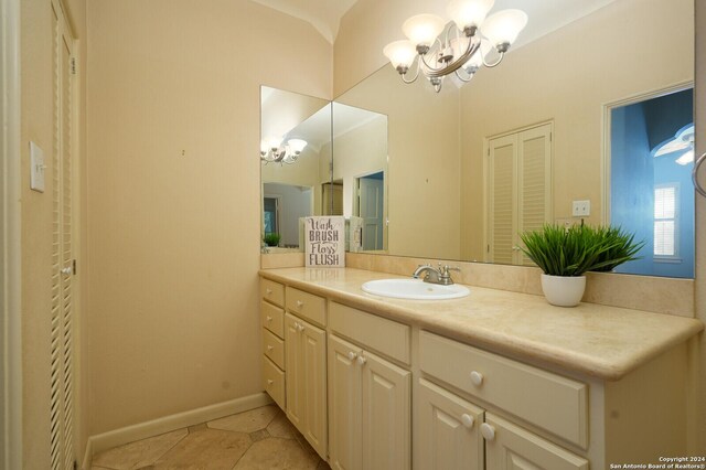 bathroom featuring baseboards, tile patterned flooring, vanity, and a notable chandelier