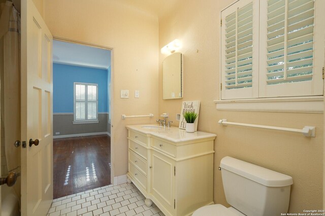 bathroom with toilet, tile patterned flooring, baseboards, and vanity