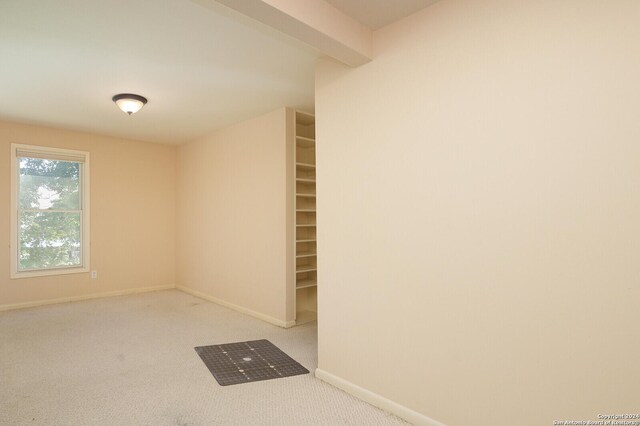 carpeted spare room with beam ceiling and baseboards