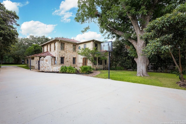 mediterranean / spanish-style home featuring stone siding, a front lawn, and driveway