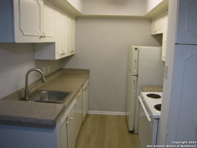 kitchen featuring light wood-type flooring, white cabinets, electric stove, and sink