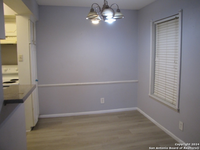 unfurnished dining area with light hardwood / wood-style floors and an inviting chandelier