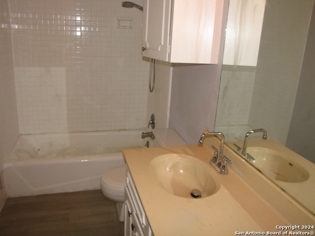 full bathroom featuring tiled shower / bath combo, vanity, toilet, and wood-type flooring