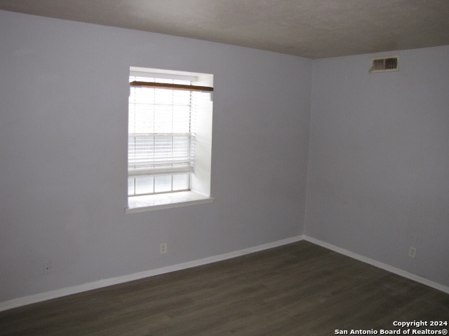 empty room featuring a textured ceiling and dark hardwood / wood-style floors