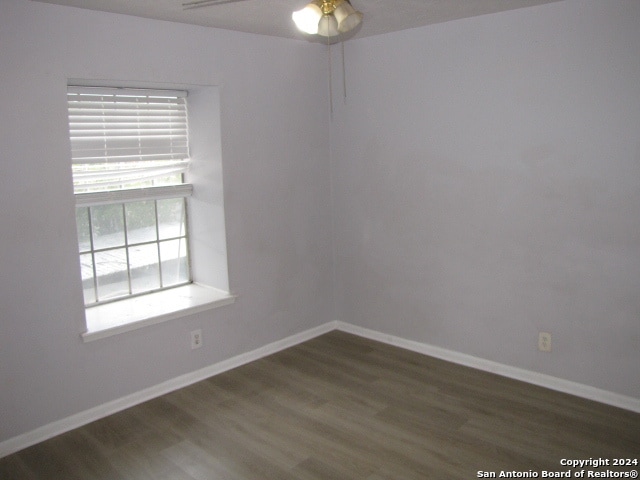 empty room featuring a wealth of natural light, ceiling fan, and dark hardwood / wood-style floors