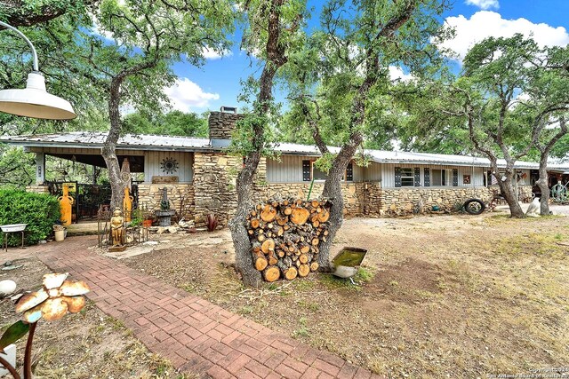 back of property with stone siding, metal roof, and a chimney