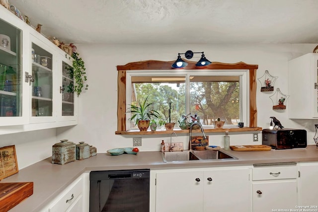 kitchen with black dishwasher, light countertops, glass insert cabinets, white cabinetry, and a sink