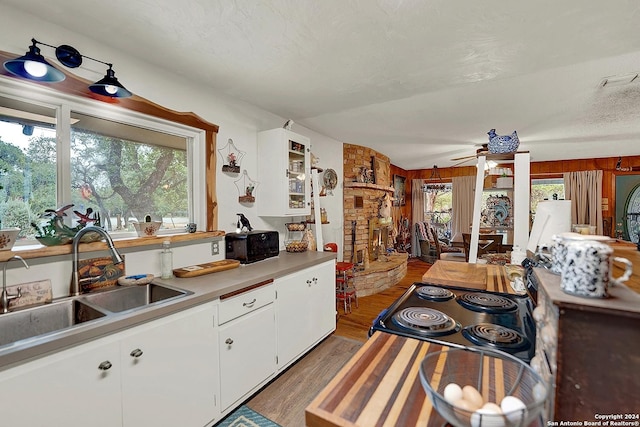 kitchen featuring light countertops, white cabinets, a sink, a textured ceiling, and wood finished floors