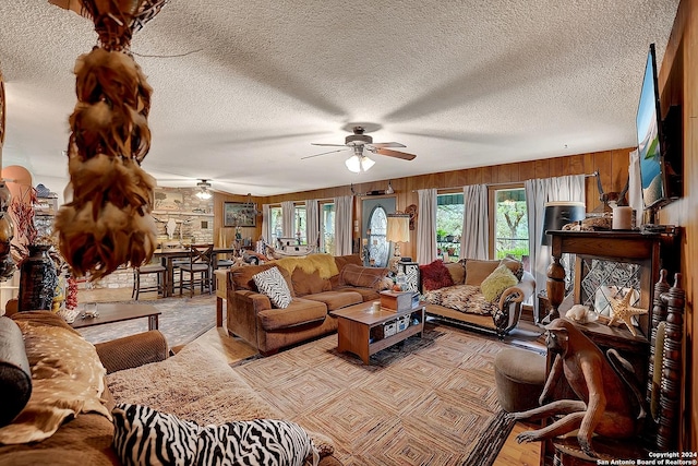 living room with a textured ceiling, a ceiling fan, and wooden walls