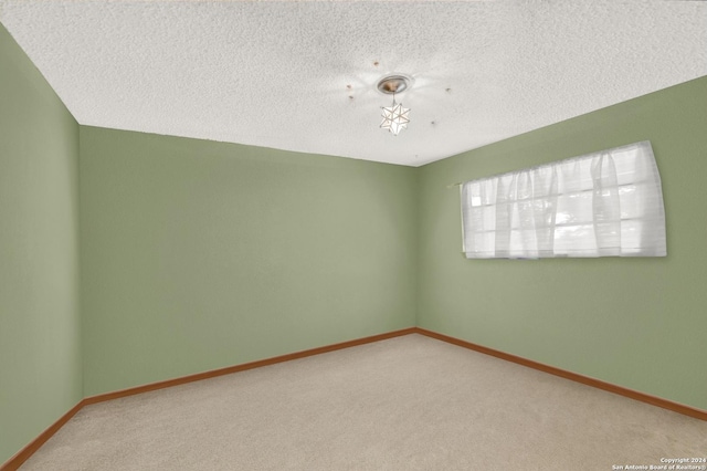 carpeted spare room featuring baseboards and a textured ceiling