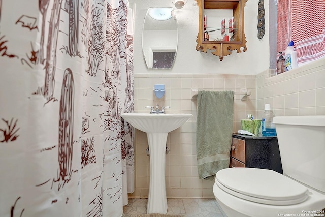 full bath featuring toilet, a wainscoted wall, and tile walls