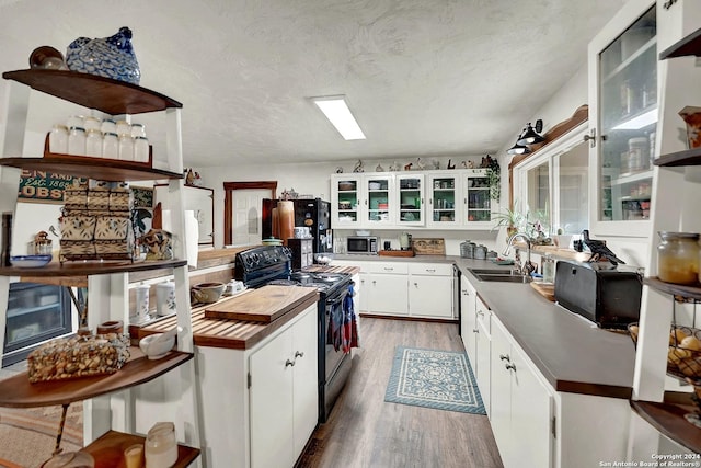 kitchen with light wood-style flooring, black range with electric stovetop, a sink, white cabinets, and stainless steel microwave