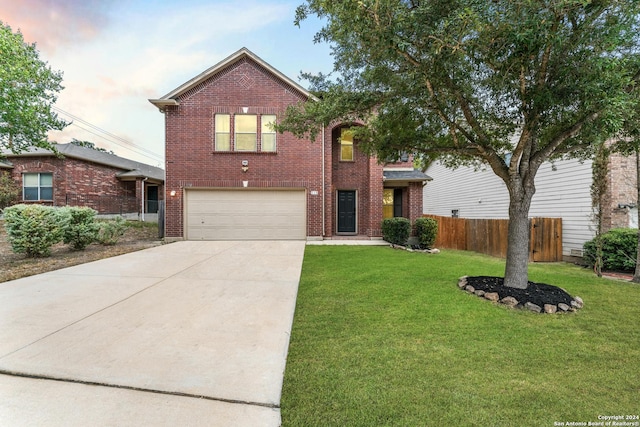 traditional-style house featuring fence, concrete driveway, a front yard, a garage, and brick siding