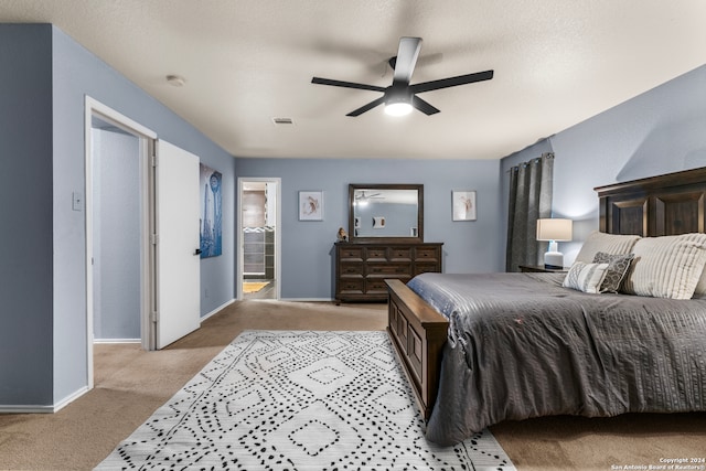 bedroom featuring ensuite bath, light colored carpet, ceiling fan, and a textured ceiling