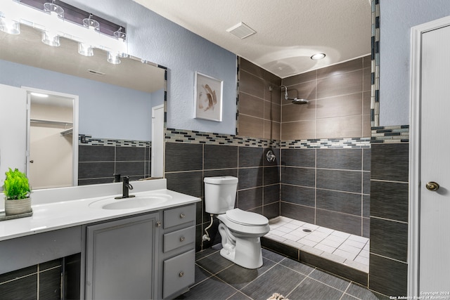 bathroom featuring vanity, toilet, tile walls, and a tile shower