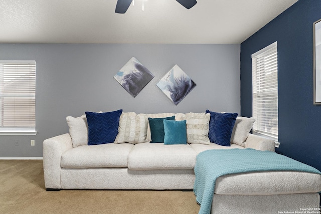 living area with baseboards, carpet floors, and a ceiling fan