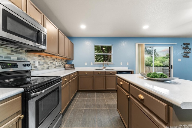 kitchen featuring a sink, stainless steel appliances, tasteful backsplash, and light countertops