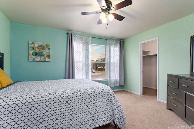 carpeted bedroom featuring a textured ceiling, a closet, ceiling fan, and a spacious closet