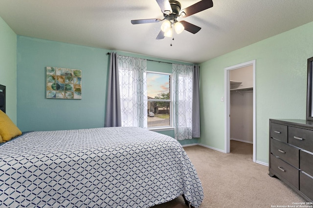 bedroom with light carpet, a spacious closet, baseboards, and ceiling fan