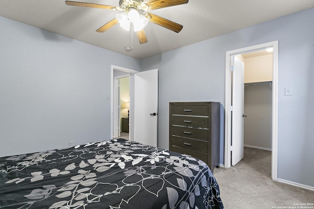 bedroom with a spacious closet, baseboards, ceiling fan, light colored carpet, and a closet