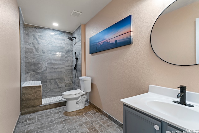 bathroom featuring vanity, toilet, and a tile shower