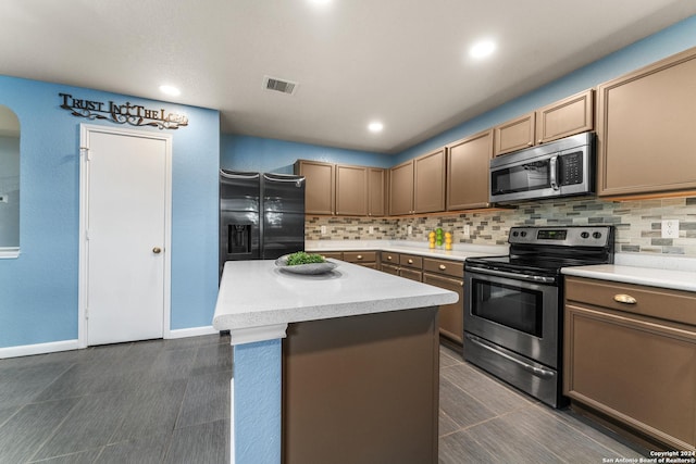 kitchen featuring visible vents, dark tile patterned floors, tasteful backsplash, stainless steel appliances, and light countertops