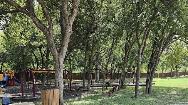 view of community with playground community, a yard, and fence