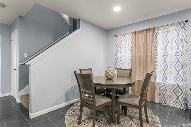 dining space with stairs, dark tile patterned floors, and baseboards