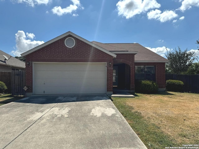 single story home with brick siding, fence, a front yard, a garage, and driveway